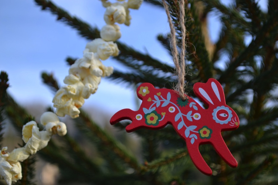 Wooden hare decoration on a real Christmas tree with popcorn garland